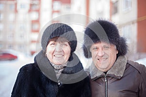 Mature couple on  street in winter near multistory houses