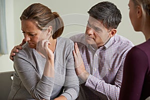 Mature Couple Talking With Counsellor As Man Comforts Woman