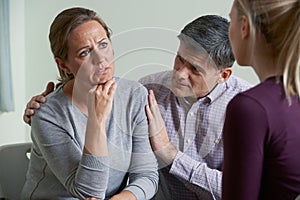 Mature Couple Talking With Counsellor As Man Comforts Woman