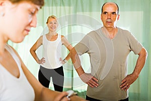 Mature couple with trainer at gym