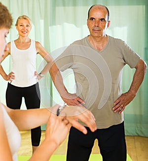 Mature couple with trainer at gym