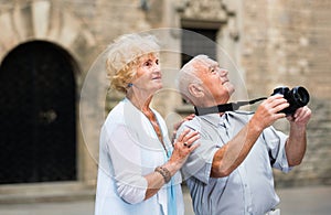 Mature couple on traveling together, photographing city attractions with camera