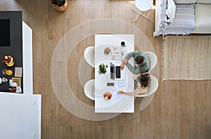 Mature couple using laptop computer sitting at table in living room. Top view.