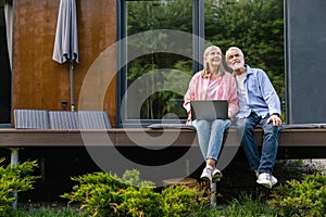 Mature couple using laptop in front of solar panels.