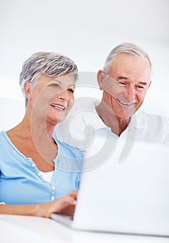 Mature couple using laptop. Happy mature woman and man using laptop at home.