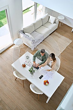 Mature couple using laptop paying bills sitting at home living room. Top view.