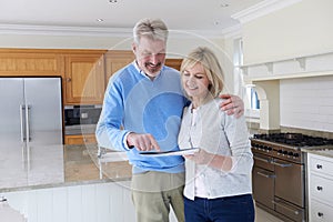 Mature Couple Viewing New Home Standing In Kitchen Looking At Br