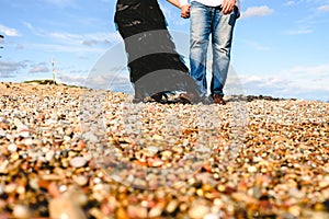 Mature couple walking on the beach by the hand of day