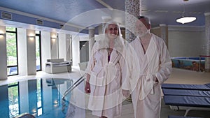 Mature couple walking hand in hand to hotel pool