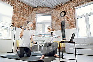 Mature couple using laptop while training with sport tools