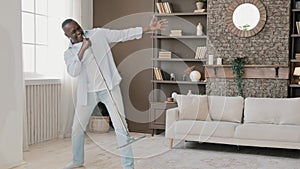 Mature crazy funny African American excited senior retired man washing floor in home apartment active dancing moving to