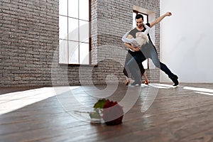 Mature dance instructor tangoing with aged woman at the ballroom