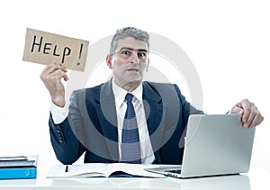 Mature desperate businessman suffering stress working at computer desk holding sign asking for help looking stressed overworked