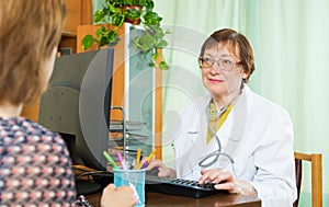 Mature doctor behind computer with patient