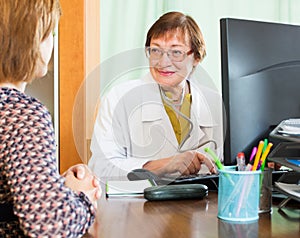 Mature doctor behind computer with patient