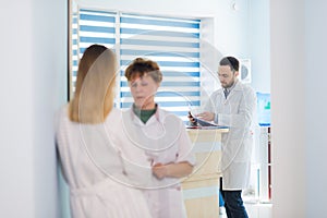 Mature doctor discussing with nurse in a hallway hospital. Doctor discussing patient case status with his medical staff