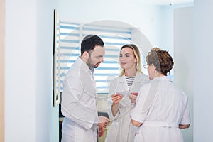 Mature doctor discussing with nurses in a hallway hospital. Doctor discussing patient case status with his medical staff