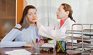Mature doctor examining ear of teenage girl