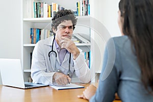 Mature doctor listening to problems of female patient