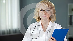 Mature doctor looking into camera guaranteeing high quality of medical services