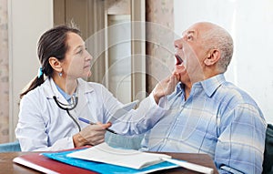 Mature doctor looks the mouth of patient