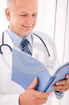 Mature doctor male look down in document photo