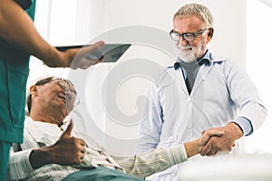 Mature doctor and senior patient in hospital ward.