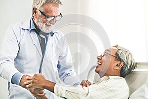 Mature doctor and senior patient in hospital ward.