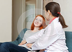 Mature doctor touching belly of teenager