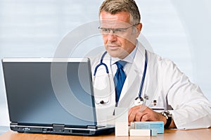 Mature doctor working on laptop