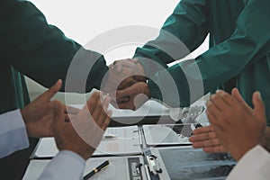 Mature doctors and young nurses stacking hands together at hospital. Close up hands of medical team stacking hands. Group of