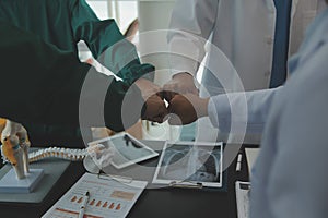 Mature doctors and young nurses stacking hands together at hospital. Close up hands of medical team stacking hands. Group of