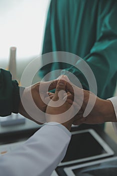 Mature doctors and young nurses stacking hands together at hospital. Close up hands of medical team stacking hands. Group of