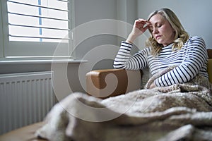 Mature Economically Inactive Woman Suffering With Long Term Illness Sitting On Sofa At Home photo