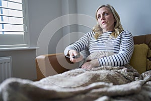 Mature Economically Inactive Woman Suffering With Long Term Illness On Sofa At Home Watching TV photo
