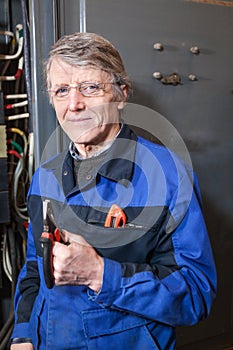 Mature electrician with pliers in his hands standing near high voltage box