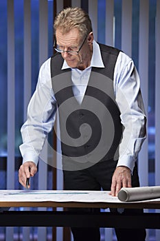 Mature engineer, architect or businessman standing at a desk
