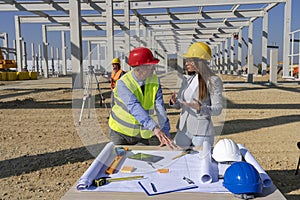 Mature Engineer and Female Architect Checking the Construction Blueprint on Construction Site