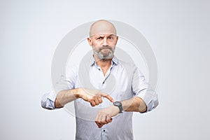 Mature european businessman impatiently pointing to his watch. Why are you late concept.