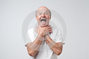 Mature european man in white tshirt shouting and suffocate because painful strangle. Health problem. photo