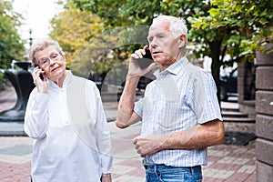 Mature european woman and man talking on the phone in summer park