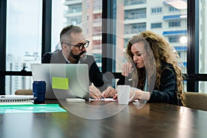 The mature executive is explaining project detail to permed hair female officer in the conference room. She is listening with an