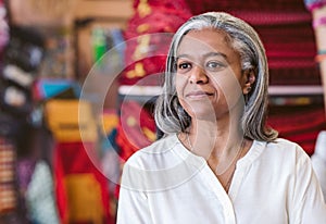 Mature fabric shop owner standing in her colorful store