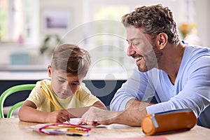 Mature Father At Home In Kitchen Helping Son With Homework