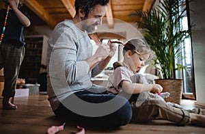 Mature father with small son and daugther resting indoors at home, playing and combing hair.
