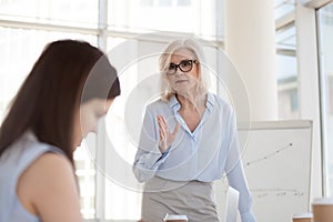 Mature female boss scolding intern for bad work results close up photo