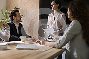 Mature female boss talking to business team, standing at table