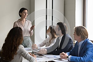 Mature female boss talking to employees on office meeting