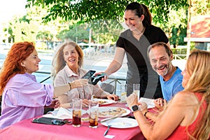 Mature female customer paying the restaurant bill with a virtual mobile card.