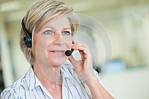 mature female customer-services worker wearing headset